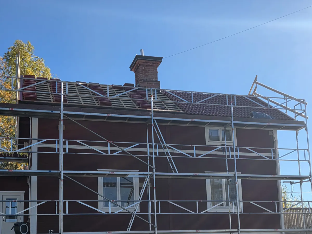 Hus med ställning där de gamla takpannorna håller på att rivas och läkten syns